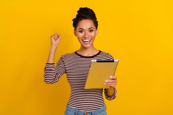 Photo of delighted crazy person raise fist hold tablet luck triumph attainment isolated on yellow color background. - Φωτογραφία, εικόνα