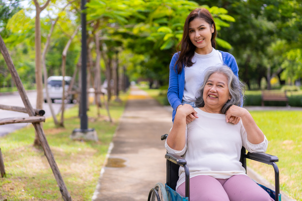 Cuidador asiático cuidadoso o enfermera que cuida al paciente en silla de ruedas. Concepto de jubilación feliz con el cuidado de un cuidador y ahorros y seguro de salud para personas mayores, una familia feliz - Foto, imagen