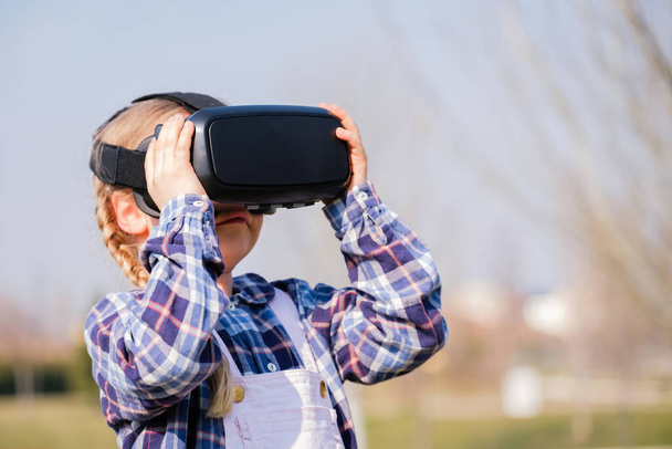 Holčička s brýlemi virtuální reality. Budoucí technologie koncept - Krásná dívka s virtuální realitou venkovní v parku - Fotografie, Obrázek
