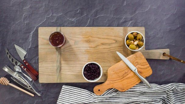 Plat gelegd. Het organiseren van gastronomische kaas, crakers, en fruit op een plank voor een grote kaasplank. - Foto, afbeelding
