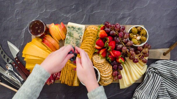 Düz yatıyordu. Büyük bir peynir tahtası için tahtanın üzerinde gurme peynir, kraker ve meyve düzenlemek. - Fotoğraf, Görsel