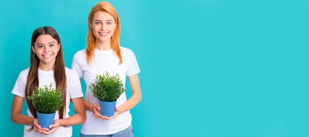 Mother and daughter child banner, copy space, isolated background. Happy woman mother and adopted daugher child smile holding pot plants blue background, fostering - Foto, immagini