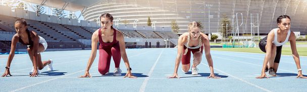 Group of determined female athletes in starting position to begin a sprint or running race on a sports track in a stadium. Focused and diverse women ready to compete in track and field olympic event. - Foto, afbeelding