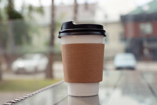 Paper takeaway cup on glass table outdoors. Coffee to go - Photo, Image