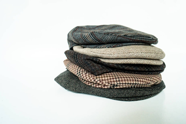Pile of classic newsboy hats and scaly hats made of tweed fabric in various colors and patterns on a white background - Fotografie, Obrázek