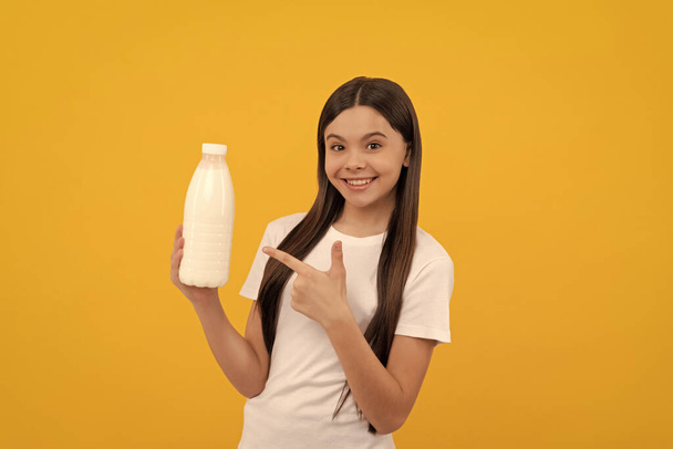 happy child point finger on dairy beverage product. teen girl going to drink milk. healthy lifestyle. chldhood nutrition. drinking per day. dairy food. yogurt for breakfast. kid hold milk bottle. - Valokuva, kuva