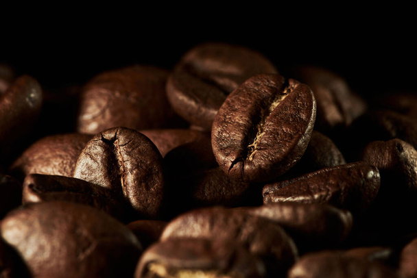 Roasted coffee beans isolated close up on black background, clipping path - Foto, Bild