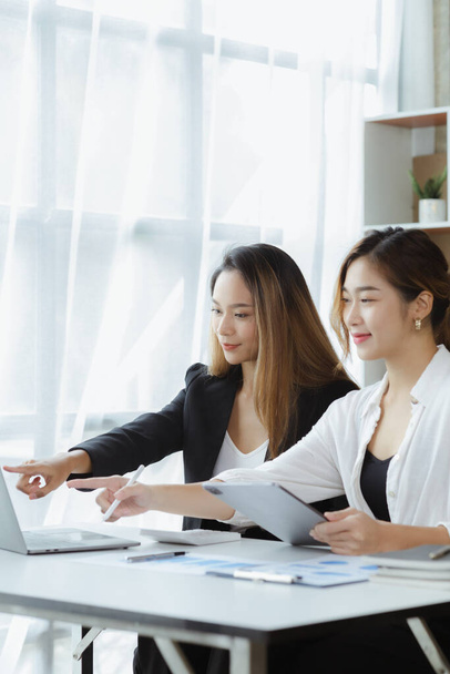 Atmosphere in the office of a startup company, two female employees are discussing, brainstorming ideas to working on summaries and marketing plans to increase sales and prepare reports to managers. - 写真・画像