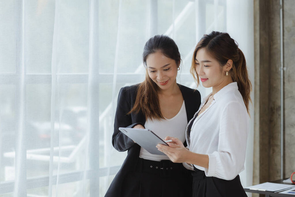Két gyönyörű ázsiai nő találkozik egy céges tárgyalóban, hogy megvitassák az üzleti terv fejlesztésére és az üzleti terv követésére irányuló terveket. Üzleti megbeszélés ötlete. - Fotó, kép
