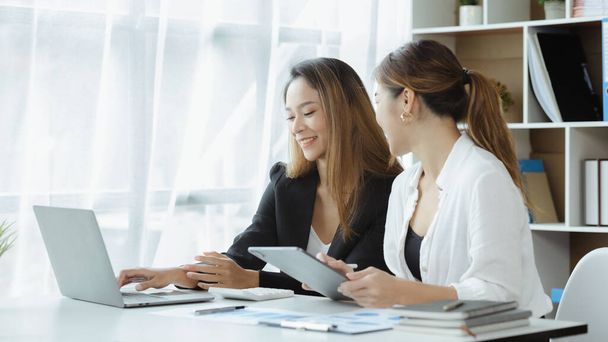 Atmosphere in the office of a startup company, two female employees are discussing, brainstorming ideas to working on summaries and marketing plans to increase sales and prepare reports to managers. - Foto, imagen