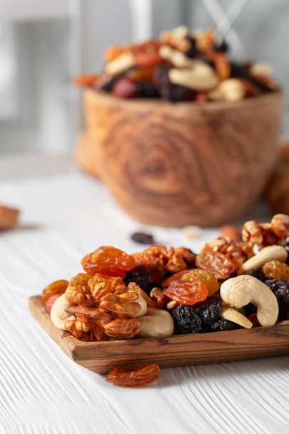 Nüsse und Rosinen auf einem weißen Holztisch mischen. Rosinen, Walnüsse, Haselnüsse, Cashewkerne, Pekannüsse und Mandeln. - Foto, Bild