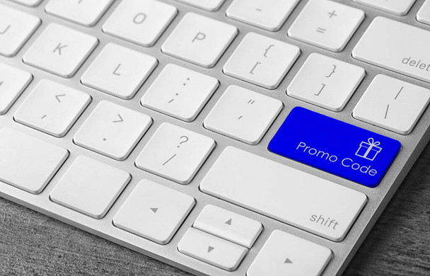 Modré tlačítko s frází Promo kód a obrázkem dárkové krabice na klávesnici počítače, detailní pohled - Fotografie, Obrázek