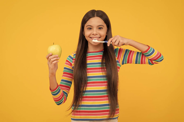 Happy girl dziecko szczoteczka zęby ze szczoteczką do zębów gospodarstwa żółty tło, zdrowe zęby. - Zdjęcie, obraz