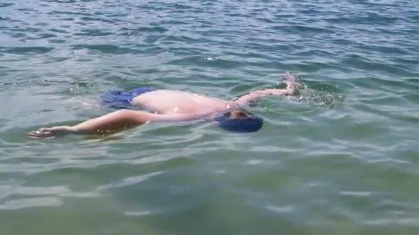 Happy Child Swimming, Diving, Holds Breath Underwater on the Beach in Sunrays. A boy learns to swim underwater in blue ocean. Sports training. Family rest, recuperation, summer vacation. Health. - Video, Çekim