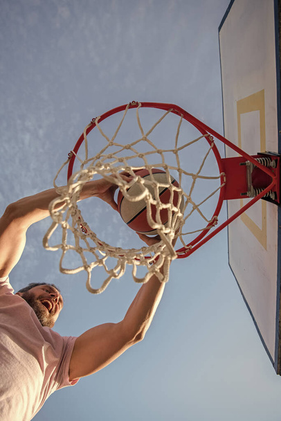 successful man with basketball ball on court. professional basketball player training outdoor. guy has sport motivation. sport and hobby. dunk in basket. slam dunk in motion. summer activity. - Φωτογραφία, εικόνα
