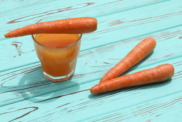 vaso de jugo de zanahoria fresca sobre fondo de madera azul con espacio para copiar - Foto, imagen