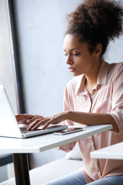 Jonge Afrikaanse Amerikaanse vrouw te typen op laptop - Foto, afbeelding