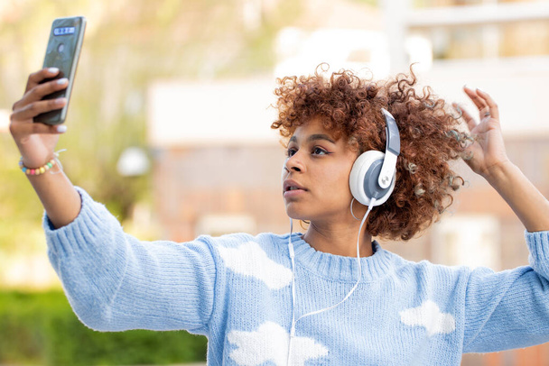 african american girl with mobile phone and headphones recording or taking photo - Photo, image
