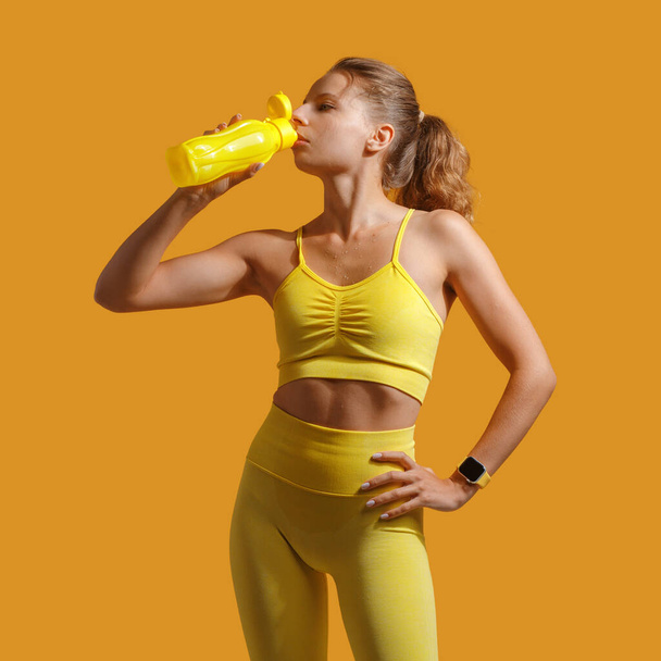 een jong aantrekkelijk meisje in gele sportkleding. Fitness. het concept van een gezonde levensstijl en sport. gele achtergrond - Foto, afbeelding