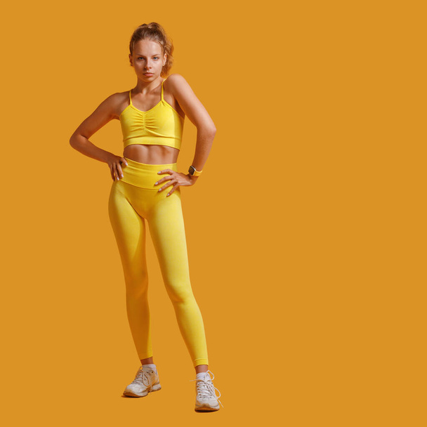 una giovane ragazza attraente in abbigliamento sportivo giallo. In forma. il concetto di uno stile di vita sano e di sport. sfondo giallo - Foto, immagini