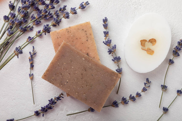 Natural lavender soap with lavender flowers on white cement background.Handmade Soap.Cosmetic product with essential oils.spa product.Space for text. Flat lay. - 写真・画像
