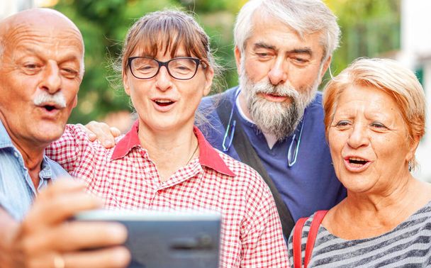 Parejas mayores tomando selfie con smartphone - Reunión de viejos amigos divirtiéndose al aire libre entre sí - Foto, imagen