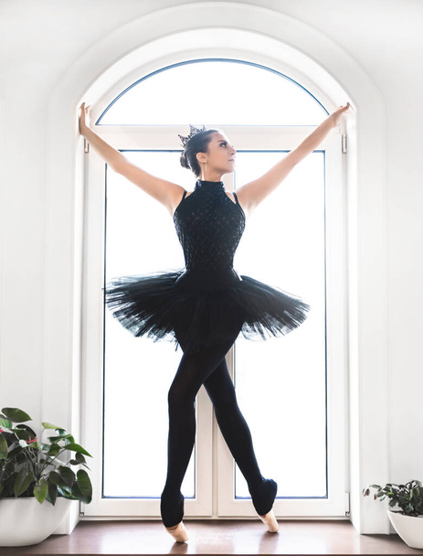 Joven bailarina de ballet practicando antes de la actuación en tutú negro, estudio de danza clásica, espacio para copiar - Foto, imagen