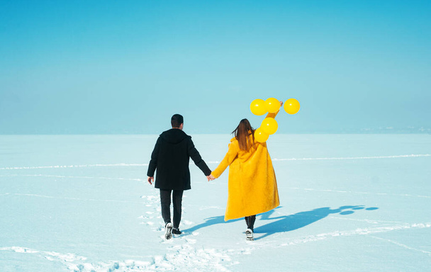 Feliz pareja ambulante. En el amor hombre y mujer caminando sobre el hielo nevado. Concepto de vacaciones de invierno. Concepto de San Valentín feliz.  - Foto, Imagen
