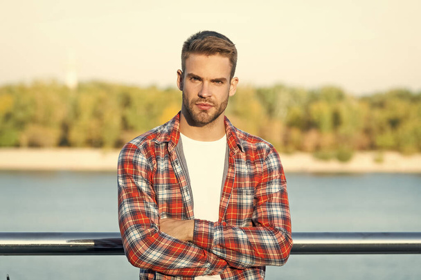 male fashion model. mens beauty. handsome man crossed hands in casual checkered shirt. young unshaven guy outdoor. - Foto, imagen