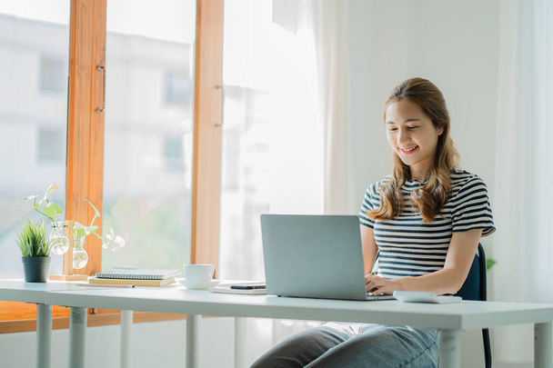 Asiatische junge Frau arbeitet mit Laptop-Computer und Finanzdokumenten zu Hause Online-Studie und Arbeitskonzept - Foto, Bild