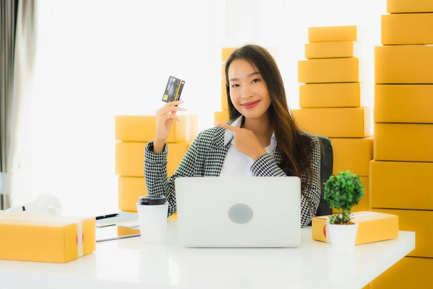 Portrét krásná mladá asijská žena práci z domova s kreditní kartou a kartonové krabice připraven k odeslání nakupování on-line - Fotografie, Obrázek