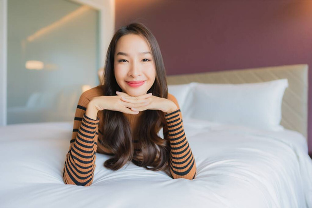 retrato hermosa joven asiática mujer sonrisa relajarse en cama en dormitorio interior - Foto, imagen