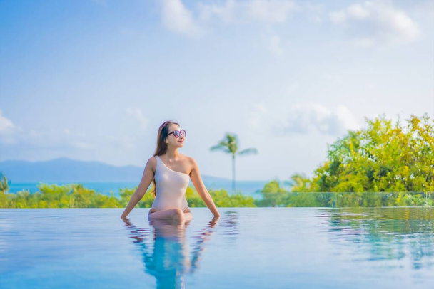Güzel bir Asyalı kadın portresi gezide deniz manzaralı açık havuzda yüzüyor. - Fotoğraf, Görsel