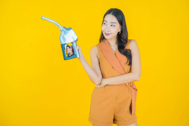 Portrait beautiful young asian woman feul gas pump on color background - Foto, Imagen