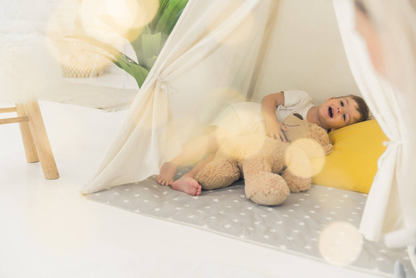 baby boy spelen met zijn teddybeer in een tent thuis, full shot kinderen concept. Hoge kwaliteit foto - Foto, afbeelding