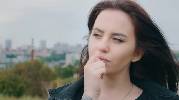 Close-up portrait young thoughtful beautiful caucasian girl brunette woman meditate outdoors hold hand to chin has question dilemma concentrated think of solution lost in thoughts dreamy looking away - Imágenes, Vídeo