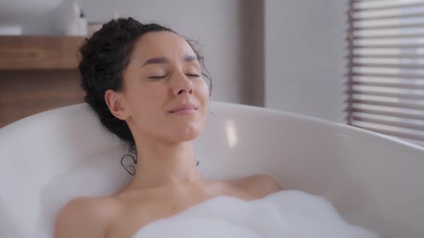Close-up young attractive relaxed woman lying in hot foam bath with eyes closed resting relaxing in bathroom happy carefree pensive dreamy girl enjoying daily hygiene routine bathing washes bodycare - Filmati, video