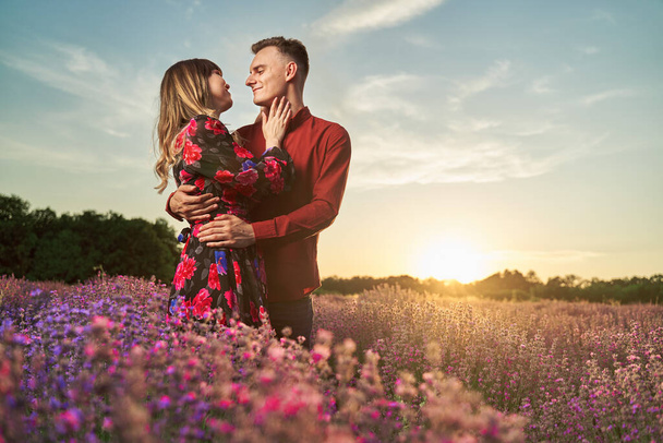Lovely young couple having a great time in a lavender field at sunset - Fotografie, Obrázek
