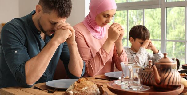 Die muslimische Familie betet vor dem Frühstück gemeinsam. Feier des Eid al-Fitr - Foto, Bild