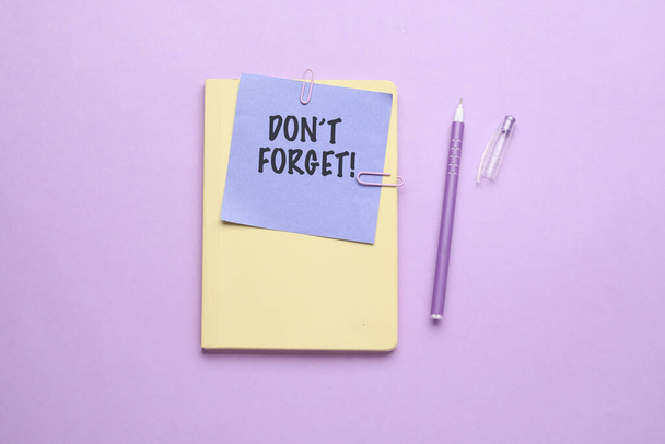 Notizbuch, Papier mit Text DON 'T FORGET und Stift auf fliederfarbenem Hintergrund - Foto, Bild