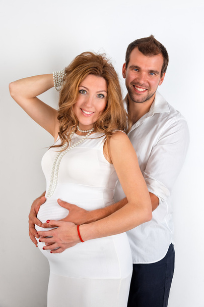 glückliches schwangere Paar in weiß gekleidet auf weißem Hintergrund - Foto, Bild