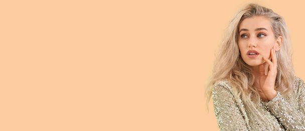 Beautiful blonde woman on beige background with space for text - Foto, imagen