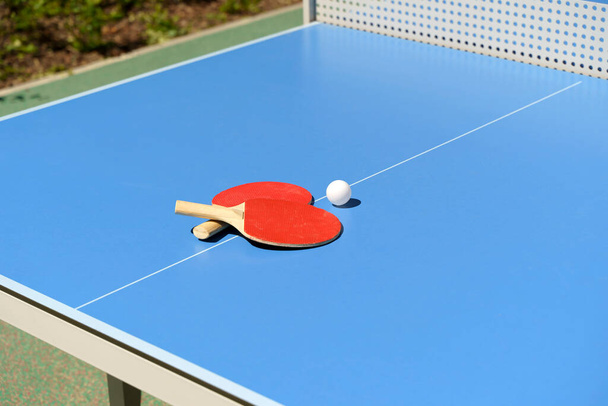 Ping pong fondo de mesa de tenis. Raquetas de tenis y una pelota sobre una mesa deportiva azul. Foto de alta calidad - Foto, imagen