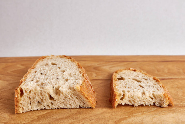 Kaksi leipäpalaa, isompi ja pienempi pala puupöydällä. Ruokakriisi. Leivän ja elintarvikkeiden hinnannousu. - Valokuva, kuva