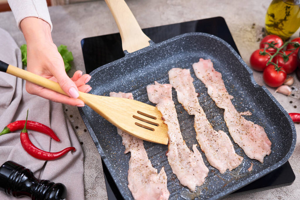 Bacon Being Cooked in grill frying pan Skillet at domestic kitchen. - Fotoğraf, Görsel