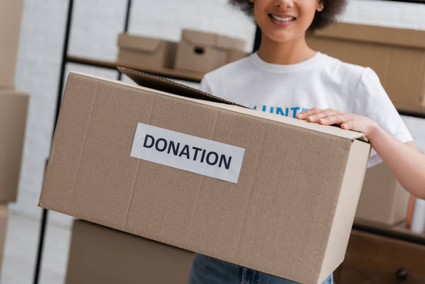 vista recortada de borrosa mujer afroamericana caja de espera con letras de donación - Foto, imagen