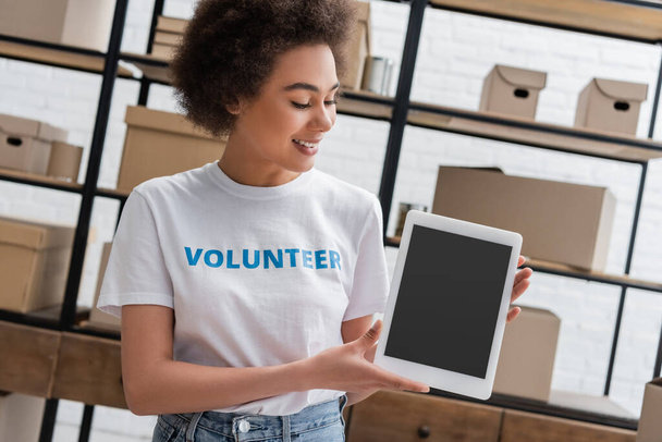 smiling african american woman holding digital tablet with blank screen in donation center - Photo, Image