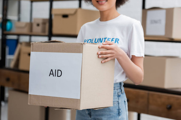 vista recortada de la caja de espera de voluntarios afroamericanos con letras de ayuda en el almacén de caridad - Foto, Imagen