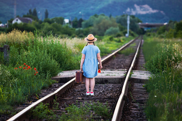 Retro styled photo of little girl with old luggage at the railways - Zdjęcie, obraz