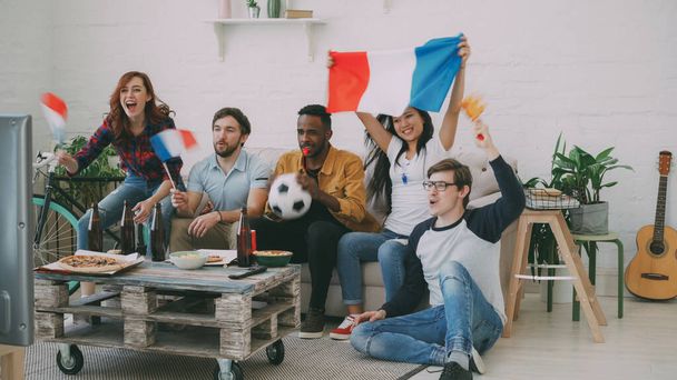 Fanów sportów wieloetnicznej grupie przyjaciół z francuskiej flagi oglądania w piłce nożnej w telewizji razem w domu wewnątrz i doping ulubionej drużyny - Zdjęcie, obraz